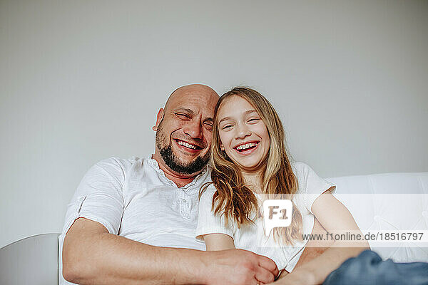 Happy father and daughter sitting together on bed at home