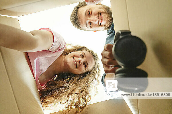 Happy young couple unboxing cardboard boxes in new home