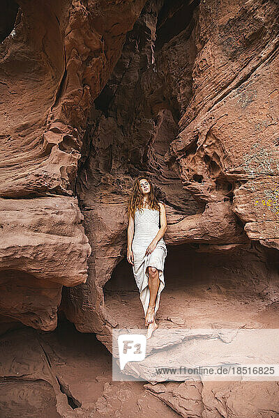 Woman leaning on rock in red sand cave