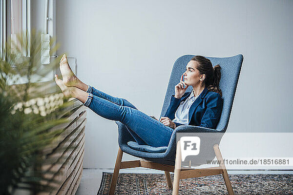 Thoughtful young businesswoman sitting on armchair