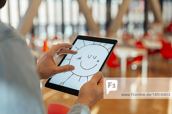 Businessman zooming design of sun on tablet PC in office