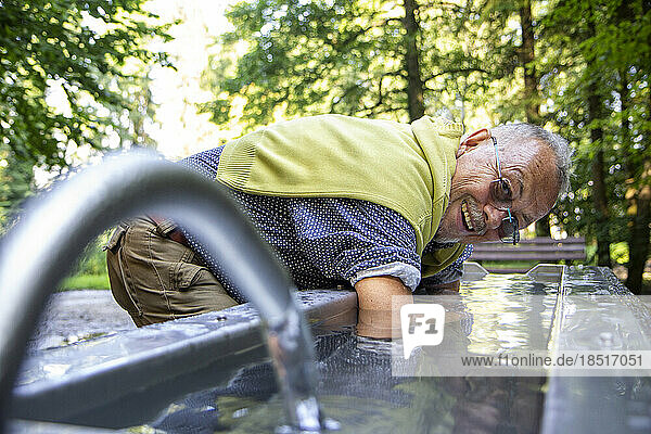 Happy senior man dipping arms in Kneipp basin