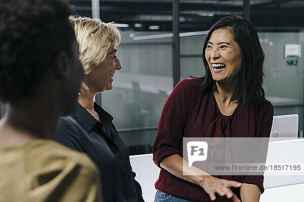 Businesswomen laughing with colleagues at office