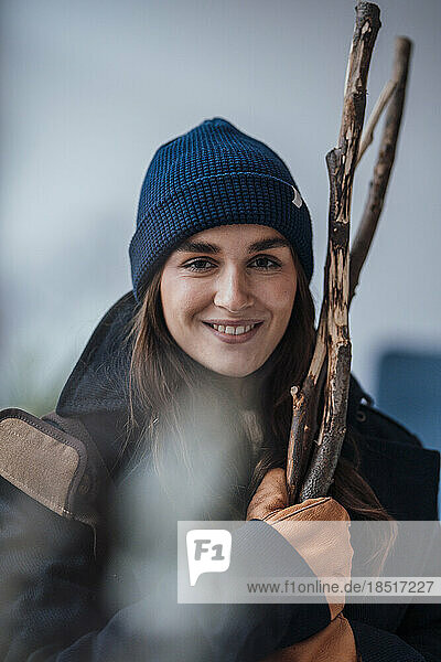 Happy young woman holding firewood