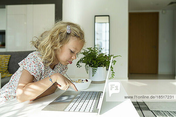 Blond girl typing on laptop at home