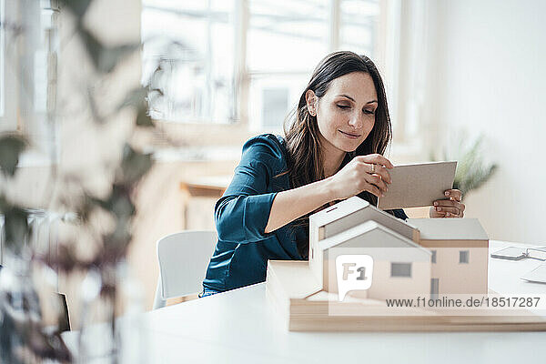 Junge Geschäftsfrau baut Hausmodell im Heimbüro