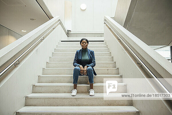 Businesswoman sitting on steps in office building
