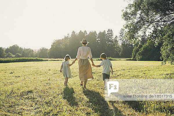 Glückliche Mutter geht mit Sohn und Tochter an einem sonnigen Tag spazieren