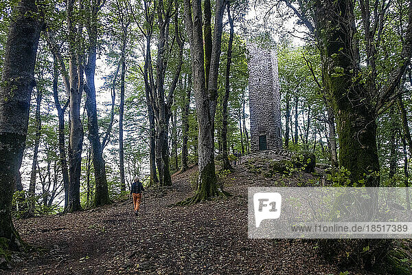 Senior woman walking towards Monti Cimini Tower in forest