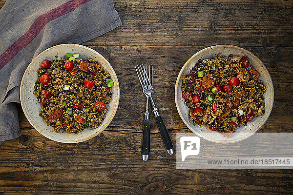 Two bowls of Beluga lentils with bulgur  tomatoes  peppers  eggplant and scallion