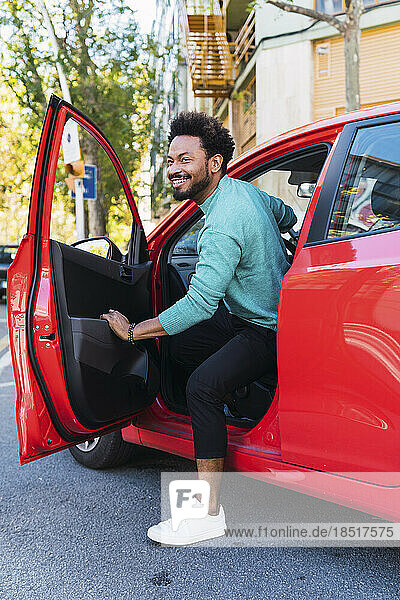 Lächelnder Mann steigt aus rotem Auto