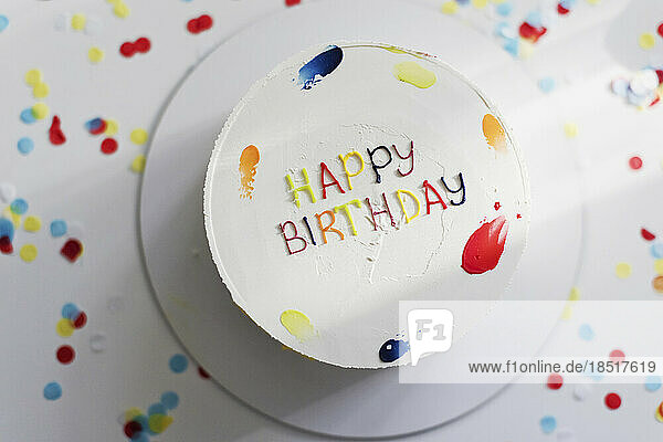 Birthday cake amidst multi colored confetti on table
