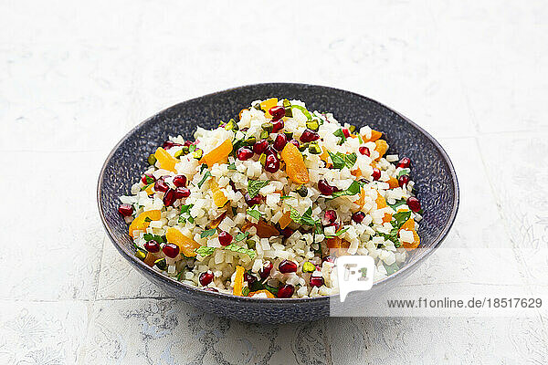 Bowl of cauliflower salad with pomegranate seeds  pistachios  mint  parsley and dried apricot