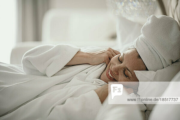 Happy woman relaxing in bedroom at home