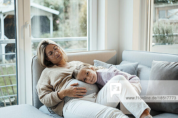 Cute girl resting head on pregnant woman's belly at home