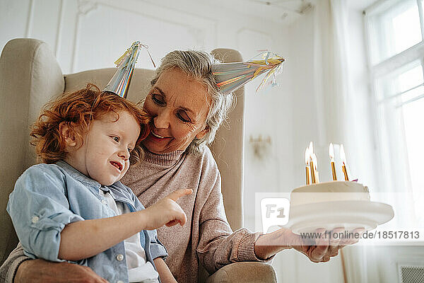Senior woman with grandson holding birthday cake at home