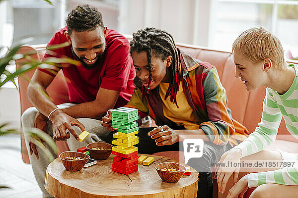 Happy multiracial friends playing block removal game at home
