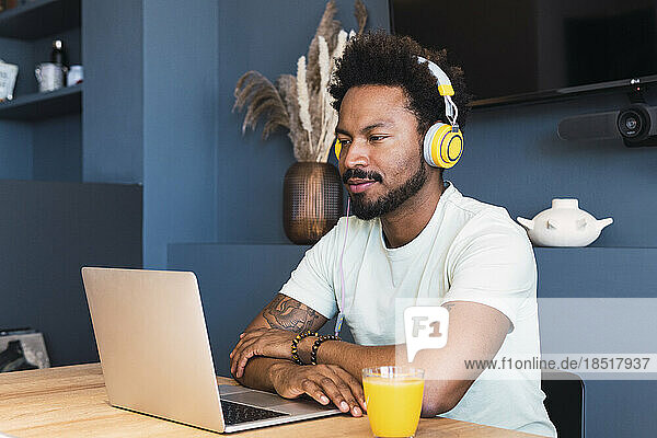 Man wearing headphones watching laptop on desk at home