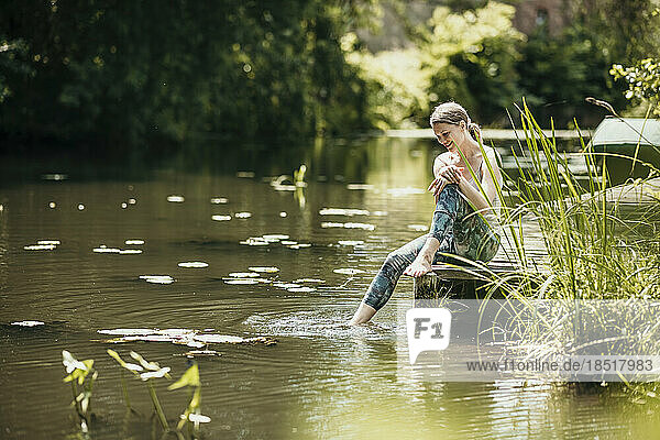 Woman dipping leg in water sitting by lake