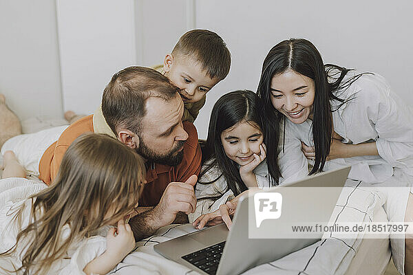 Happy family using laptop in bedroom at home
