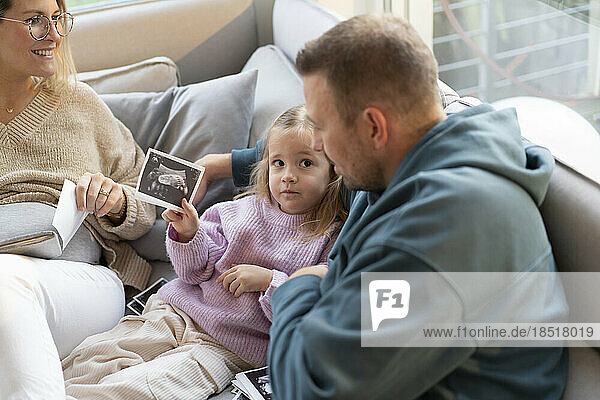 Daughter showing ultrasound photo to father at home