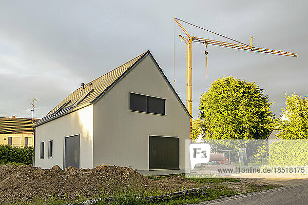Deutschland  Bayern  Außenansicht eines modernen Einfamilienhauses mit Industriekran im Hintergrund