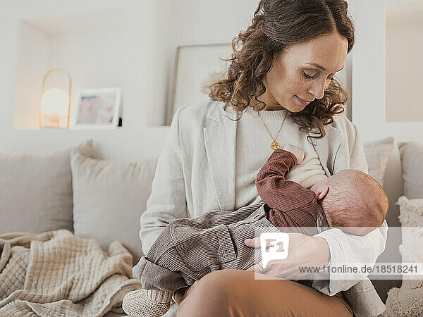 Woman breastfeeding son on sofa at home