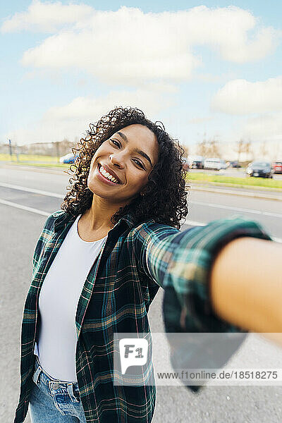 Happy young woman taking selfie on road