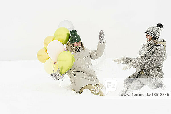 Fröhliche Freunde  die Spaß mit Luftballons im Schnee haben