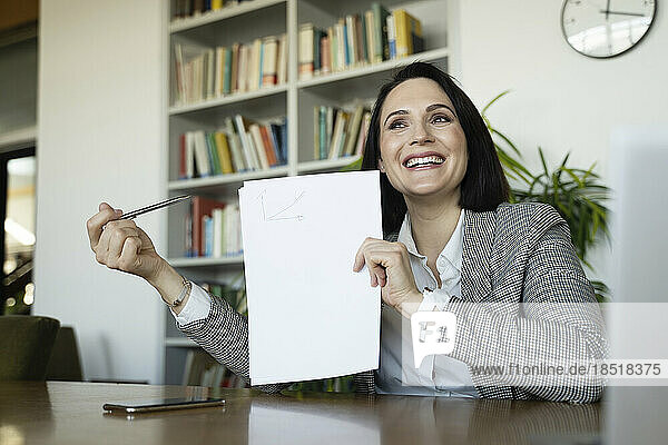 Glückliche Geschäftsfrau zeigt im Büro auf ein leeres Dokument