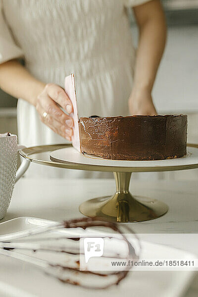 Young woman leveling sides of cake at home
