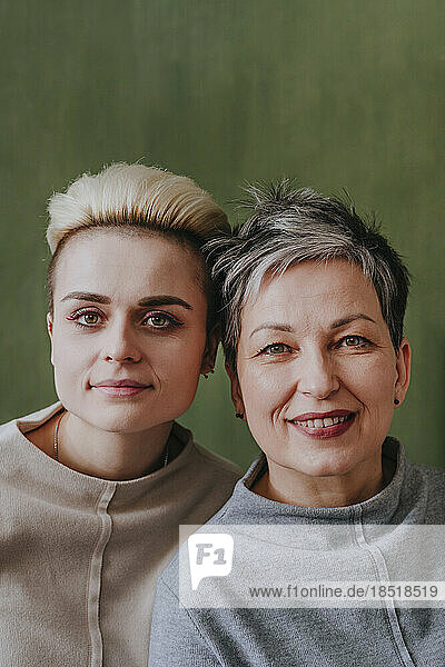 Mother and daughter with short hair in front of green wall