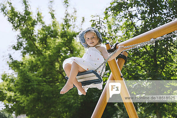 Smiling girl swinging on swing at park