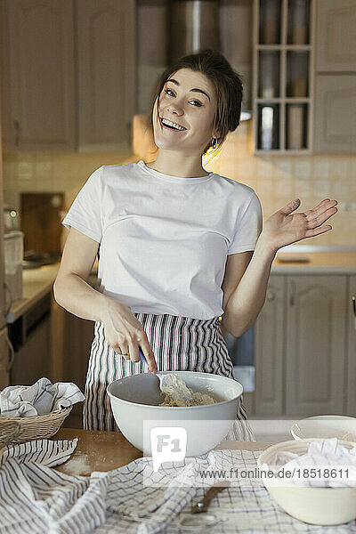 Happy young woman pointing at bread dough in bowl