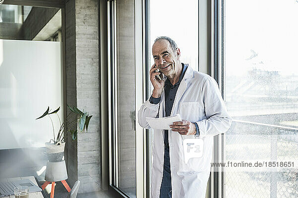 Happy doctor with prescription talking on mobile phone