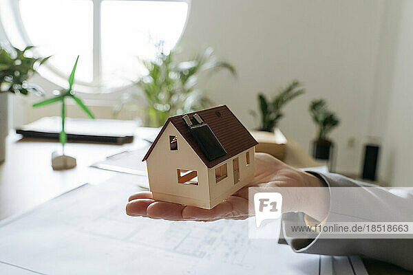 Real estate agent holding model house with solar panel
