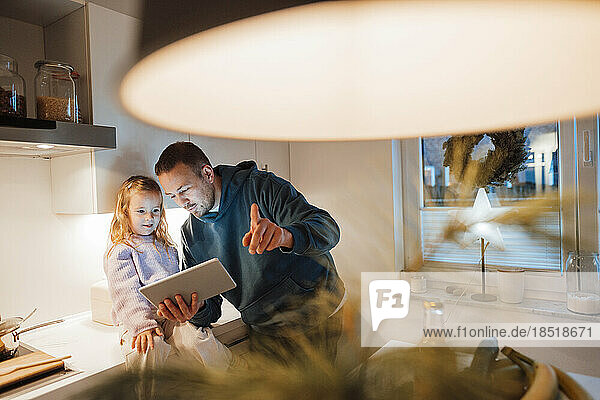 Vater teilt Tablet-PC mit Tochter in der Küche