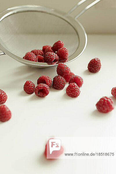 Raspberries spilled from colander on table