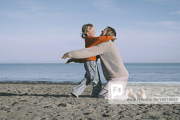 Happy mother hugging daughter at beach
