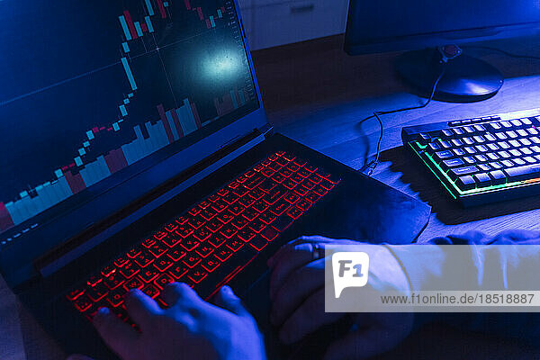 Hands of hacker using illuminated keyboard at home