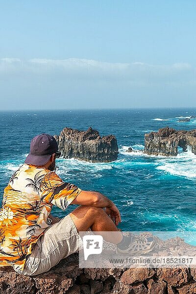 Insel El Hierro. Kanarische Inseln  Tourist Mann in den Bogen von La Tosca sitzen. Denkmal an der Küste