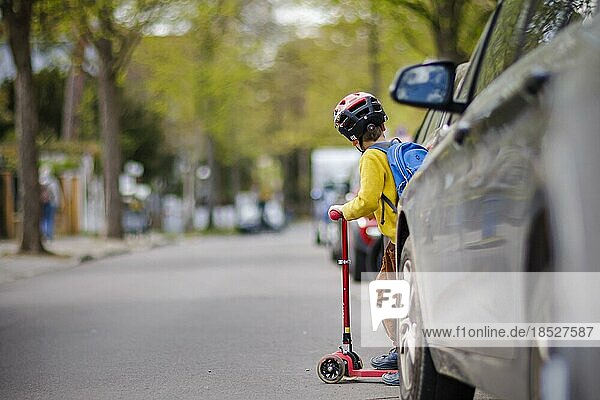 Symbolic photo on the subject of children in road traffic A little boy stands with his scooter between parked cars on a street. Berlin  26.04.2022  Berlin  Germany  Europe