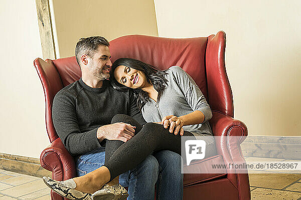Cheerful couple relaxing on armchair together 