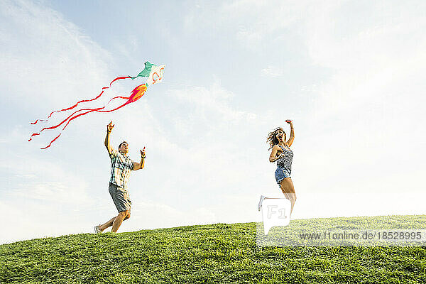 Woman and man flying kite in park 