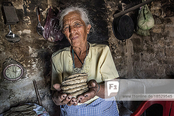 Ältere mexikanische Frau hält in ihrer Küche einen Stapel Fladenbrot in den Händen; Ejido Hidalgo  San Luis  Mexiko