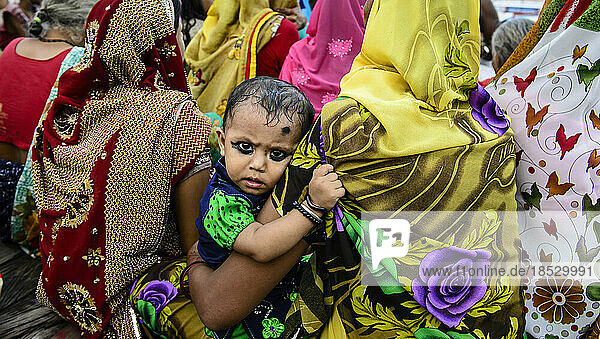 Kleines Mädchen mit geschminkten Augen  das von seiner Mutter gehalten wird; Varanasi  Indien