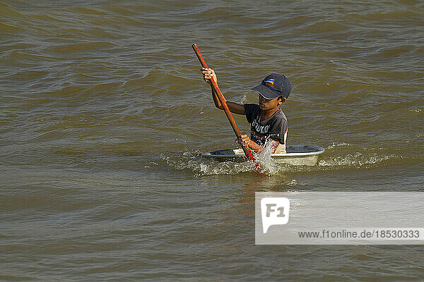 Kind steuert ein Boot auf dem Großen See oder Tonle Sap; Tonle Sap  Kambodscha