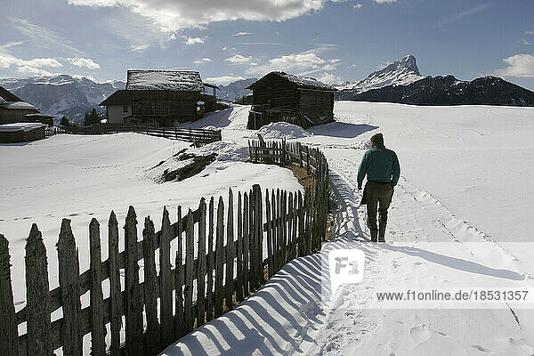 Ein Bauer geht entlang eines Zauns zu seiner Scheune und seinem Haus; La Valle  Südtirol  Italien