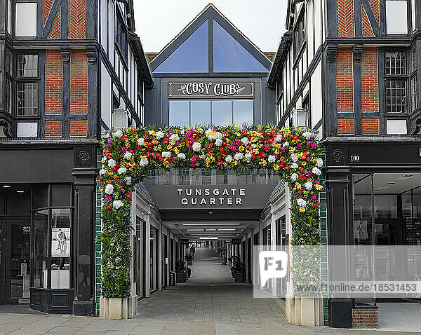 Retail buildings in Tunsgate Quarter  Guildford  UK  with decorative blossoms at the entrance of a walkway; Guildford  Surrey  England