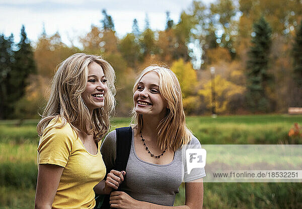 Zwei Mädchen im Teenageralter gehen an einem warmen Herbsttag zusammen in einem Stadtpark spazieren; St. Albert  Alberta  Kanada.